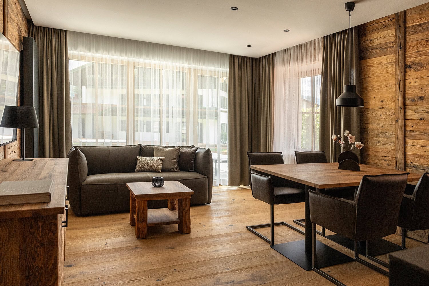 Ferienwohnung für 2 Personen mit Essbereich, Sofa, TV und großen Fenstern zur Terrasse.